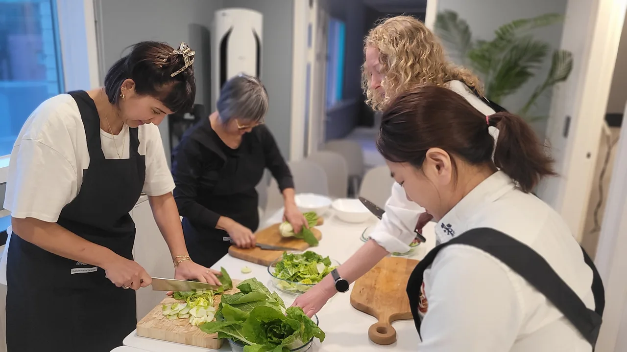 Four guests preparing vegetables together at a kitchen table during a COZE cooking class